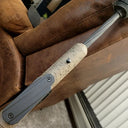 Rifle with textured stock resting on leather couch, ideal for predator hunting gear