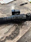 Black thermal rifle scope with control buttons and lens, on marble surface for predator hunting gear.